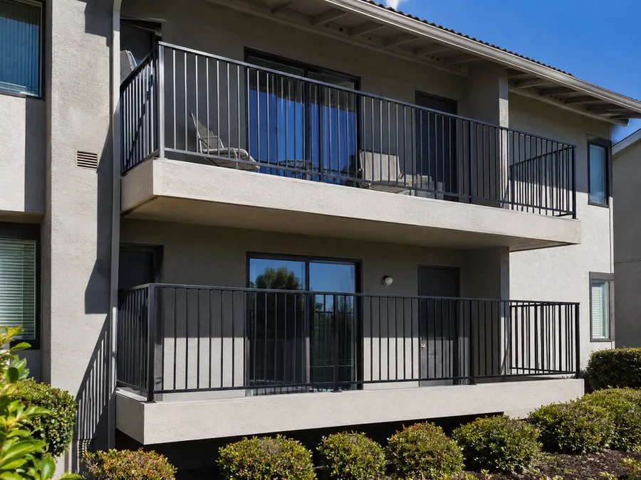 Black metal balcony guardrails on stacked concrete balconies at an apartment building