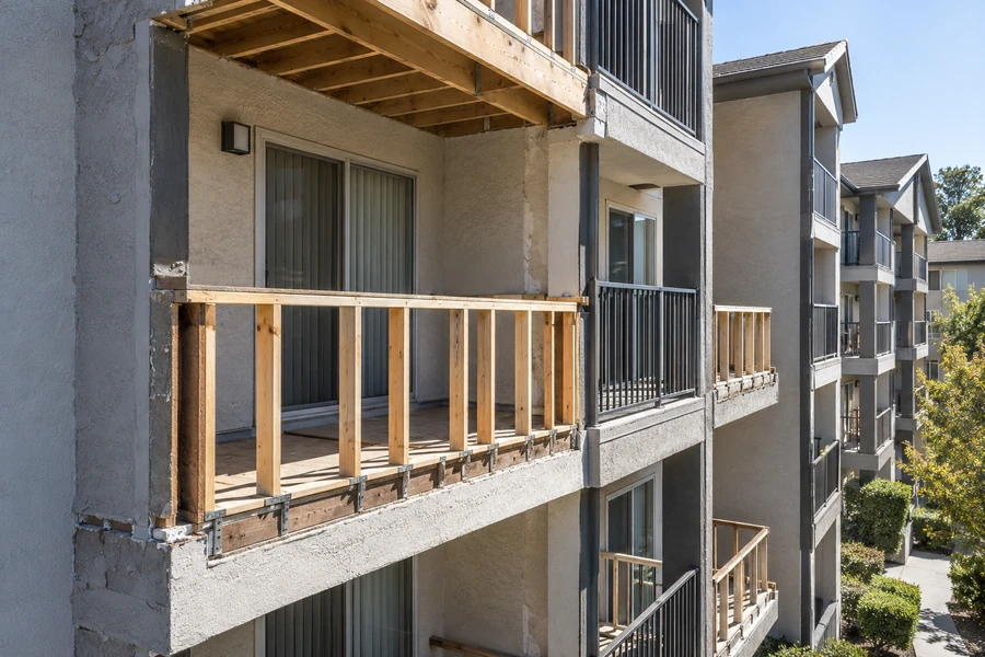 Balcony rebuilt to bare framing with new rail posts standing, neighbouring balconies also opened
