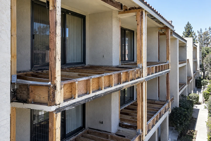 Stacked balconies stripped back, framing and posts exposed across two floors