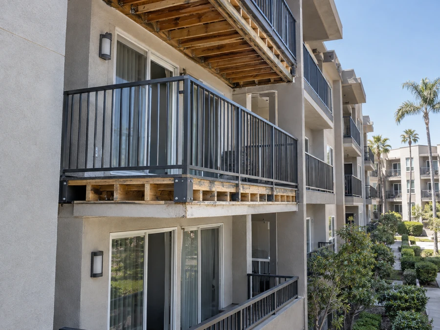 Balcony mid-remodel with new railing fitted and the original framing still exposed below