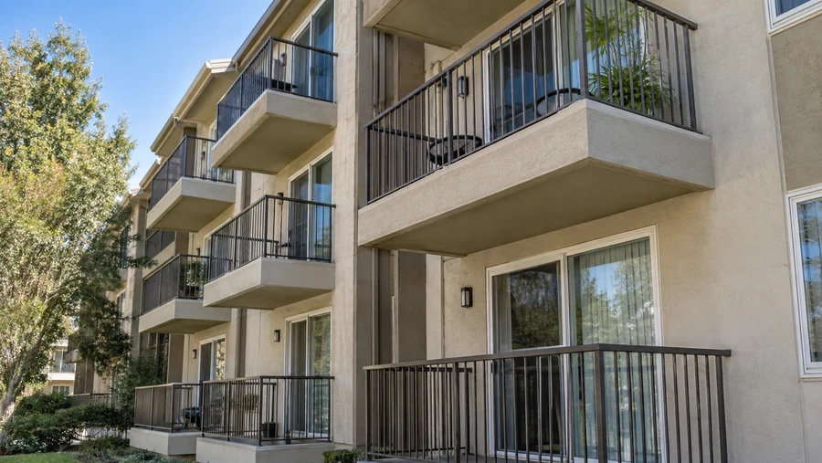 Stucco apartment building with metal railed balconies on three floors