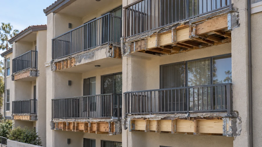 Apartment balconies with stucco removed and new lumber framing and connectors installed at the edges