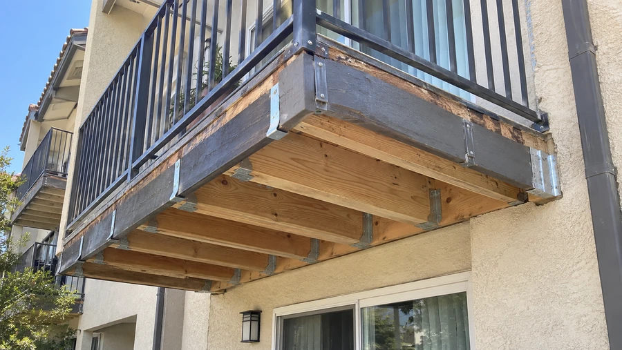 New joists hung from the wall on metal connectors alongside the original blackened rim