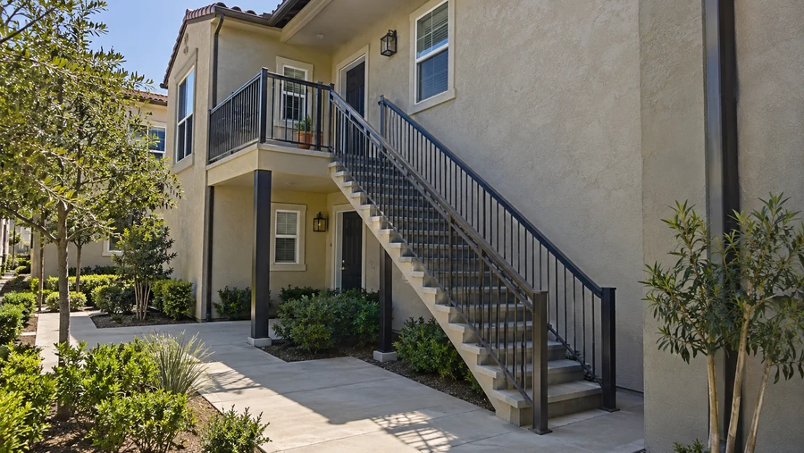 Concrete-tread balcony staircase with metal guardrails rising to an upper-floor unit