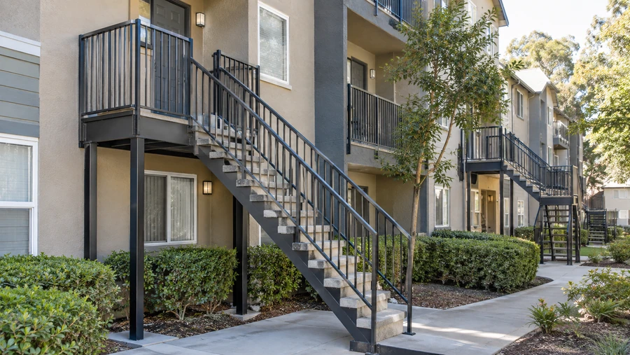Steel-stringer balcony stairs with concrete treads serving a run of upper-floor balconies