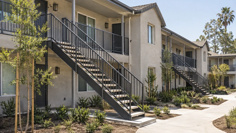 Repeating balcony staircases along an apartment elevation, each serving one upper unit