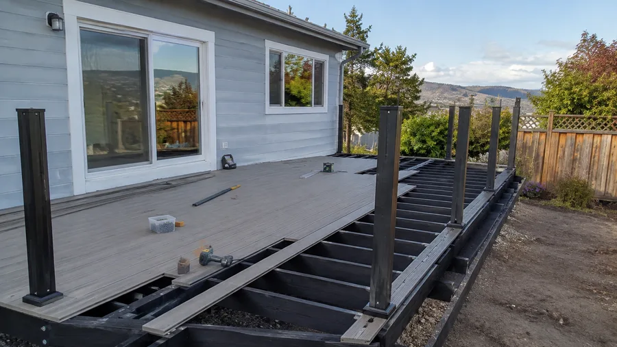 Composite decking part-laid over the frame, with guardrail posts set and boards running out