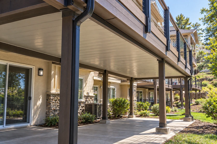 Composite deck with an enclosed underside and a downspout carrying collected water away from the structure