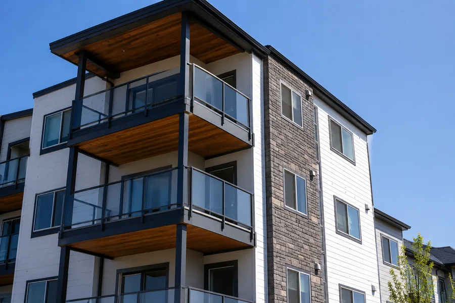 Condominium balconies with glass guardrails and wood-clad soffits on a four-story building