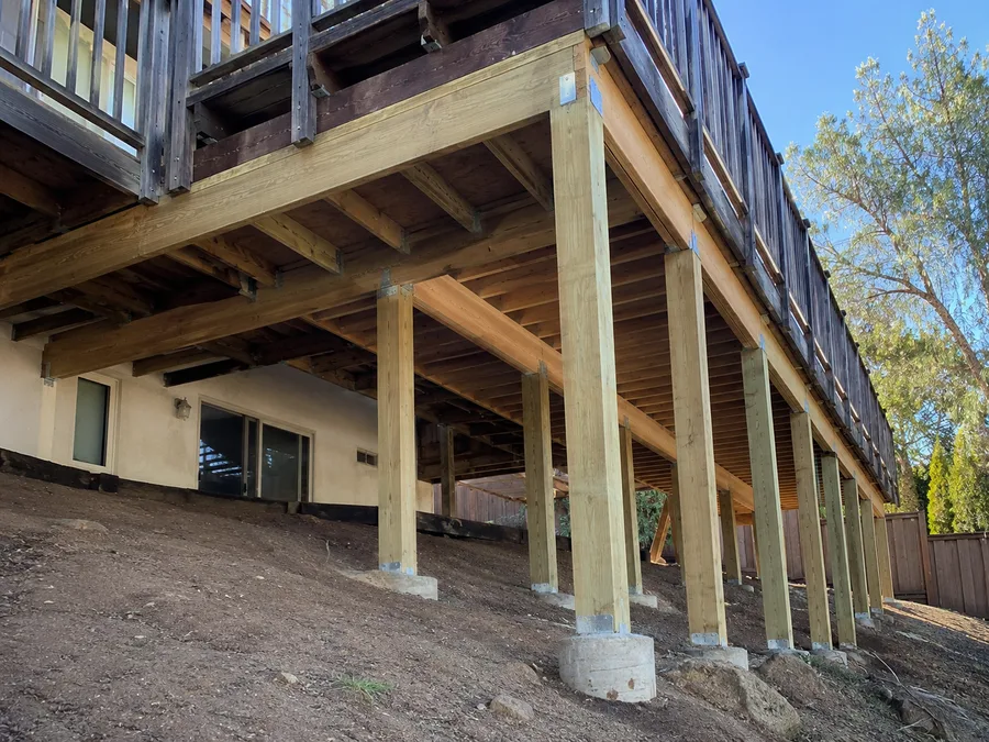 New framing and posts extending an elevated deck, set on fresh concrete piers