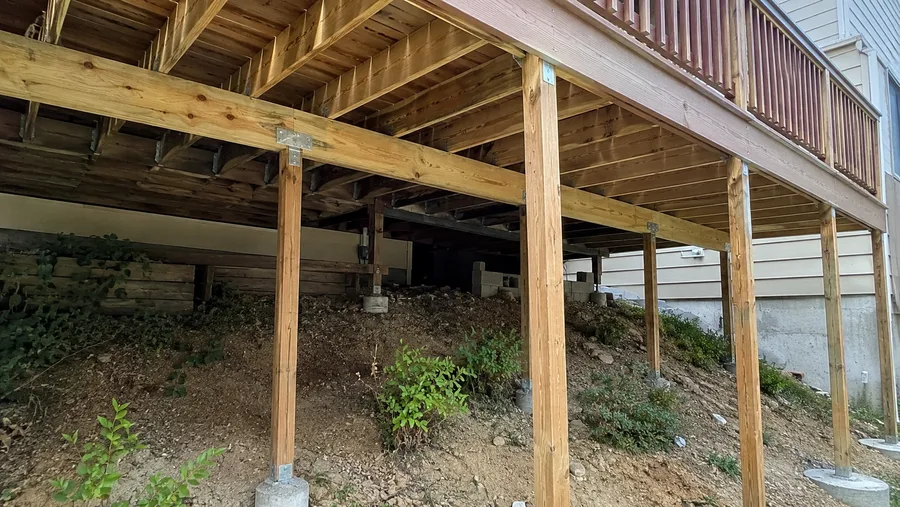 Underside of an extended elevated deck with new posts on concrete piers