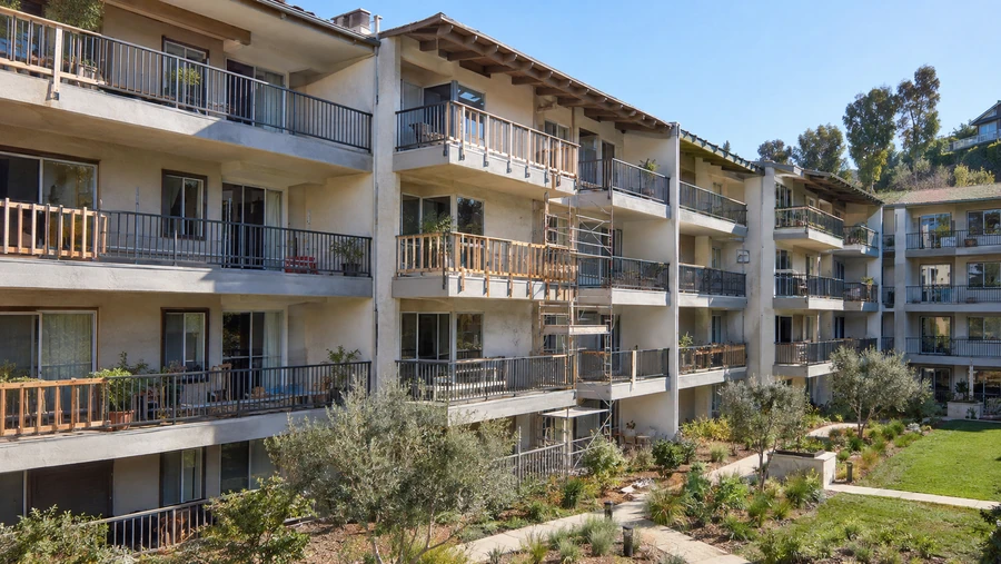 Scaffolded elevation with railing repairs in progress on upper-floor balconies