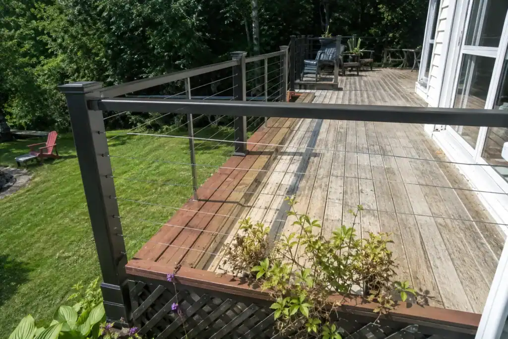New cable railing on an older weathered deck, with a fresh strip of boards where the old railing was removed