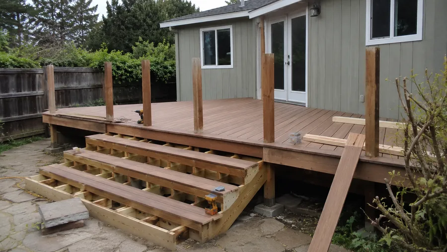 Deck rebuild in progress with new decking laid, stair stringers framed and posts set