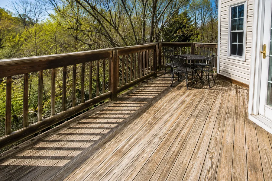 Sun-bleached deck boards and railing showing an aged, failed finish