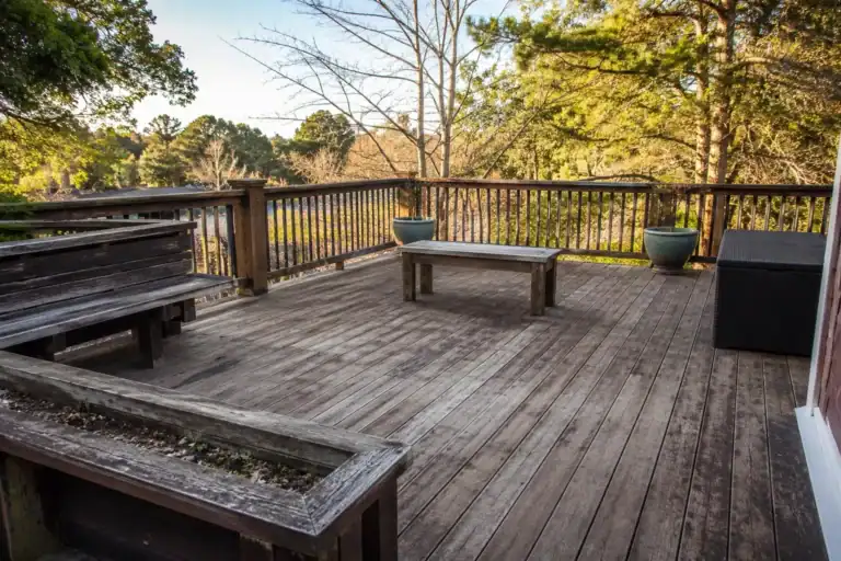 Weathered grey deck with faded boards and built-in seating, before restoration