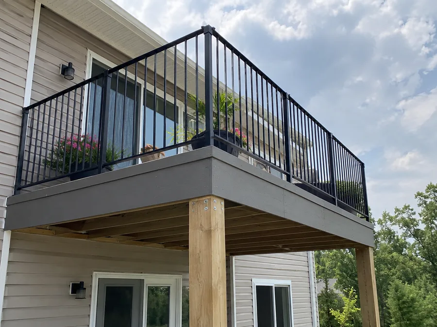 Corner of an elevated balcony with aluminum guardrails and exposed post-and-beam framing below