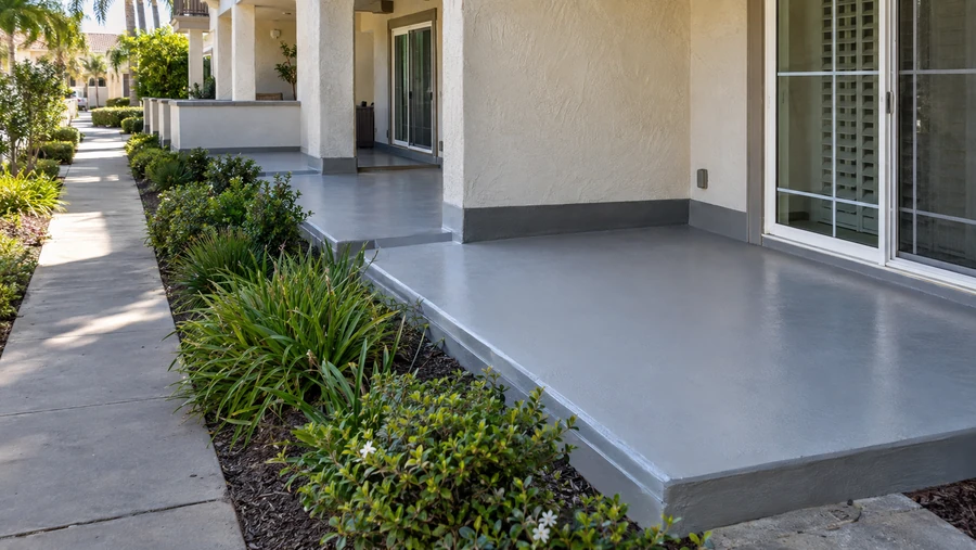 Row of ground floor patios with new gray deck coating along a multi-unit stucco building