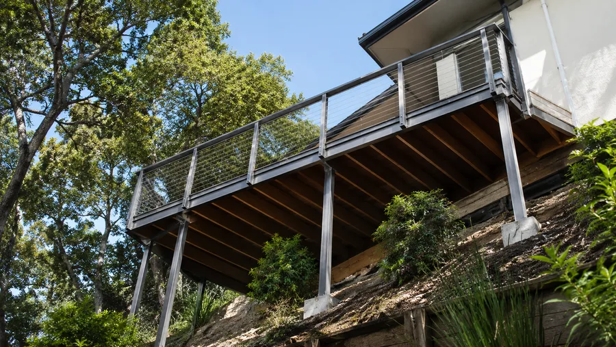 Hillside balcony structure seen from below, with steel posts on concrete piers set into the slope