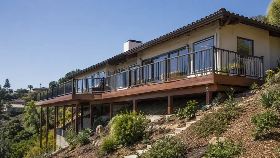 Long hillside balcony running along a house above a steep landscaped slope