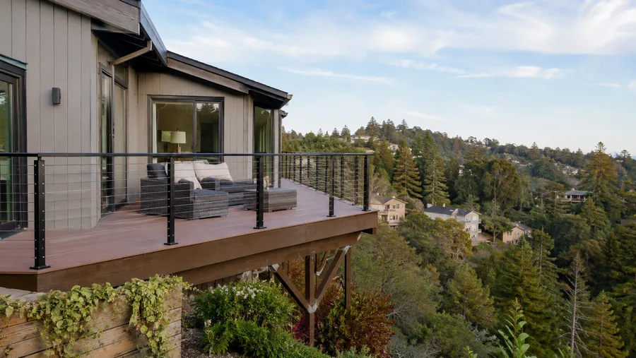Hillside balcony projecting over a wooded canyon, on braced posts below