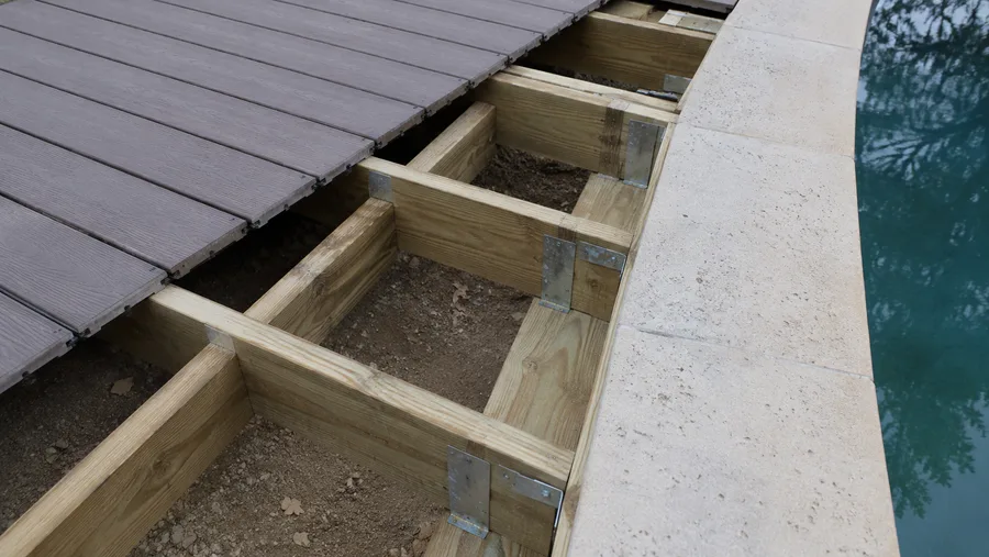 Deck frame running alongside the pool coping, independent of it, with decking part-laid
