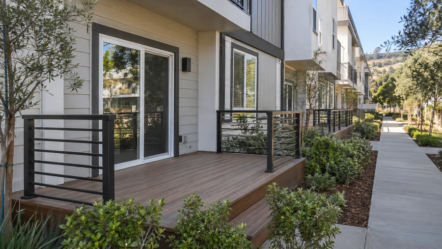 Finished patio deck with composite boards and horizontal metal guardrails at a townhome community