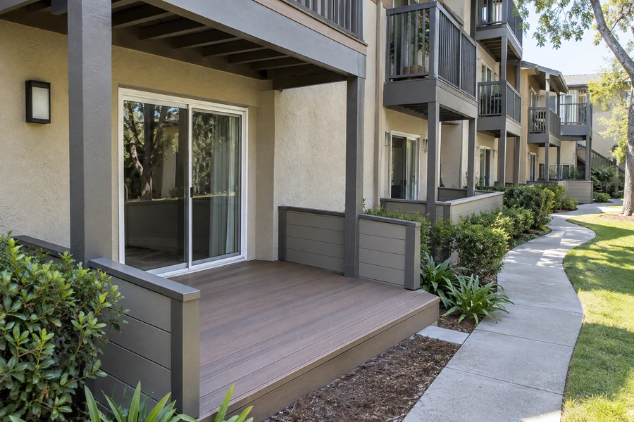 Ground floor deck with low gray privacy walls beside a curved walkway at a multi story building