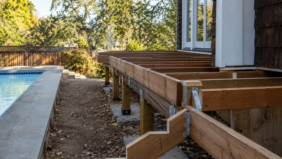 Pool deck frame alongside the pool coping, on posts and concrete piers with metal connectors