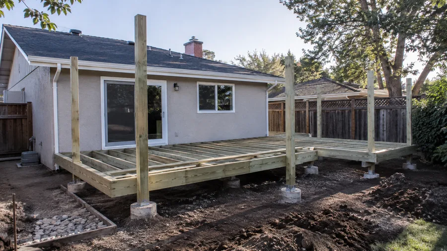 Pressure-treated deck frame on metal post bases and concrete piers, before decking