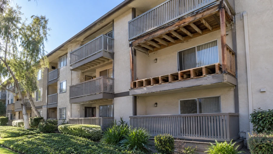 Apartment elevation with a failed balcony stripped to bare framing beside intact units