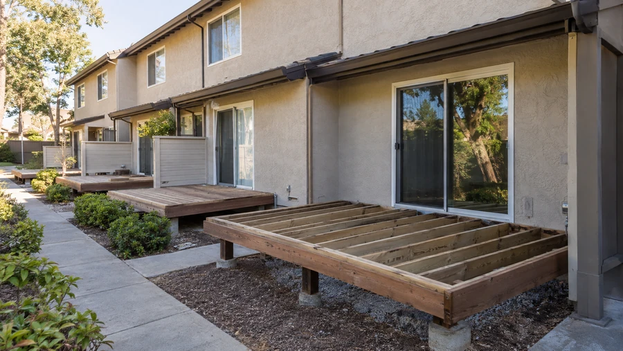 Run of patio decks at a townhome community, one stripped to framing and the others complete