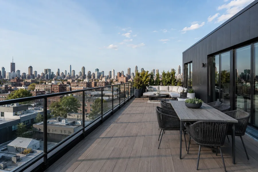 Rooftop balcony with composite decking and glass guardrails above a city skyline
