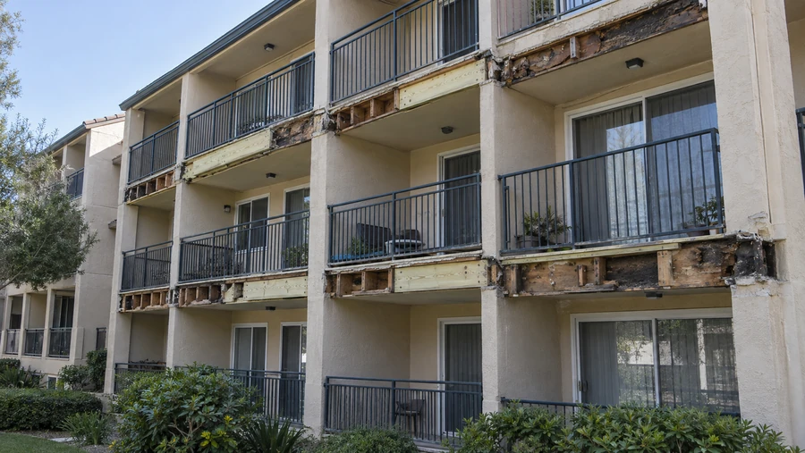 Apartment elevation with balconies opened across three floors, new material fitted among the original framing
