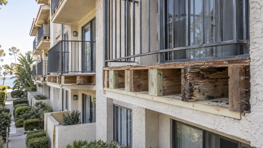 Balcony rim with rot cut out in sections and new pressure-treated blocking fitted between sound members