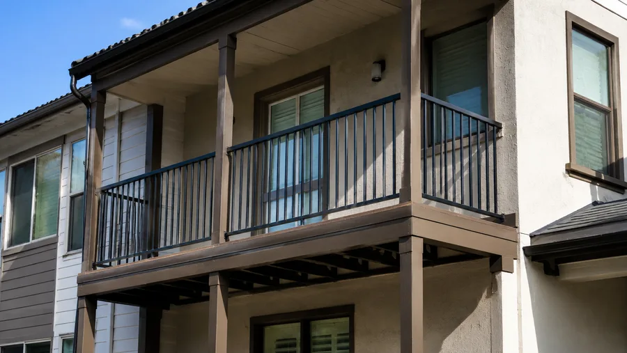 Second-floor balconies with metal guardrails and wood posts on a multifamily building