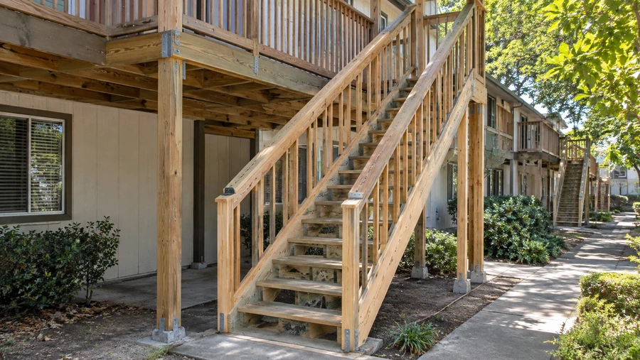 New exterior stair with guardrails and posts on metal bases at an apartment building