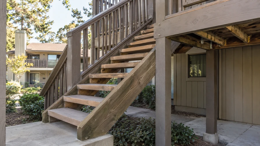 Weathered timber stair run and landing serving an upper-floor apartment walkway