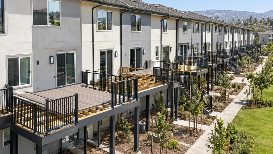 Townhome elevation with composite decks part-laid, joists visible on the units still in progress