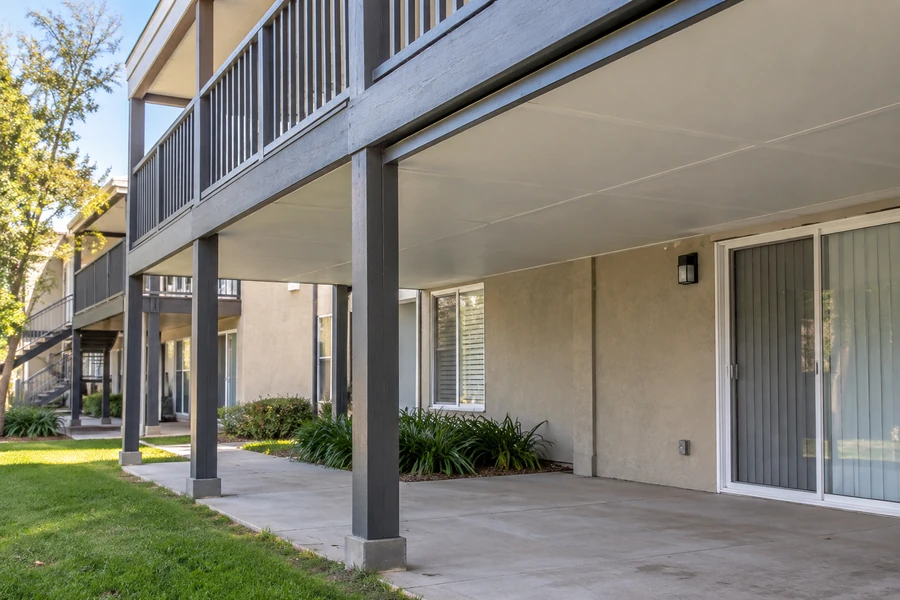 Dry ground-floor patio beneath a finished under-deck ceiling at an apartment community