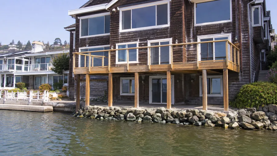 Beachfront balcony on timber posts above a rock revetment at the water&rsquo;s edge