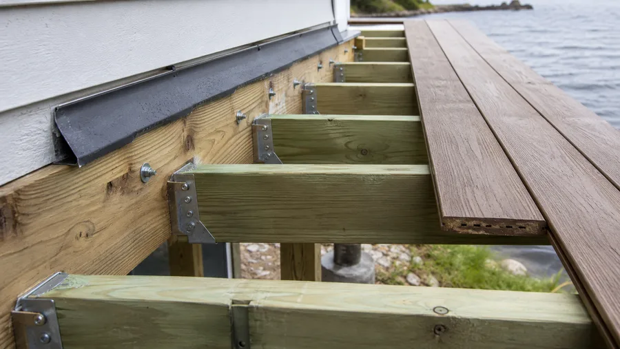 Waterfront deck ledger with flashing, joist hangers and structural bolts, with water beyond