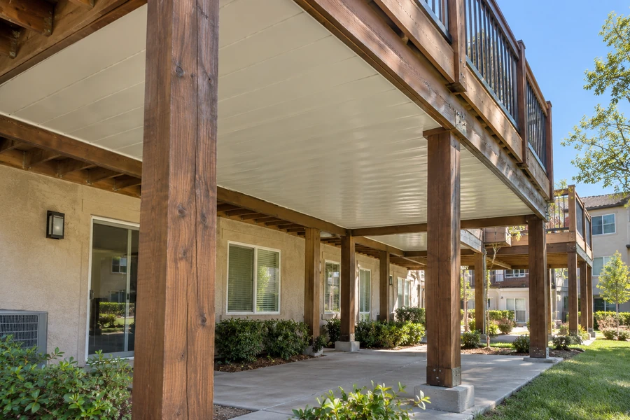 Wooden deck carried on timber posts with the underside enclosed, apartment community beyond